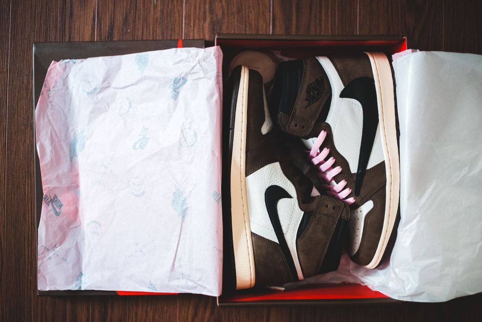 Top view of new stylish unisex sneakers in cardboard box placed on wooden floor